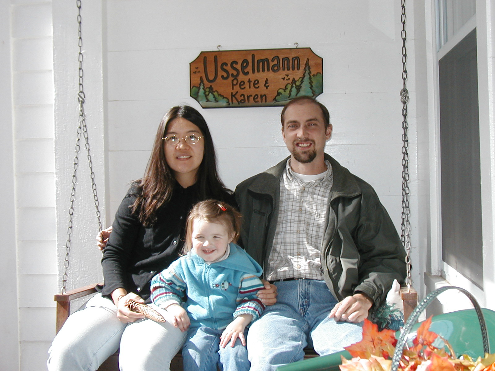 Maya, John and Debbie on a porch swing under the Usselmann sign